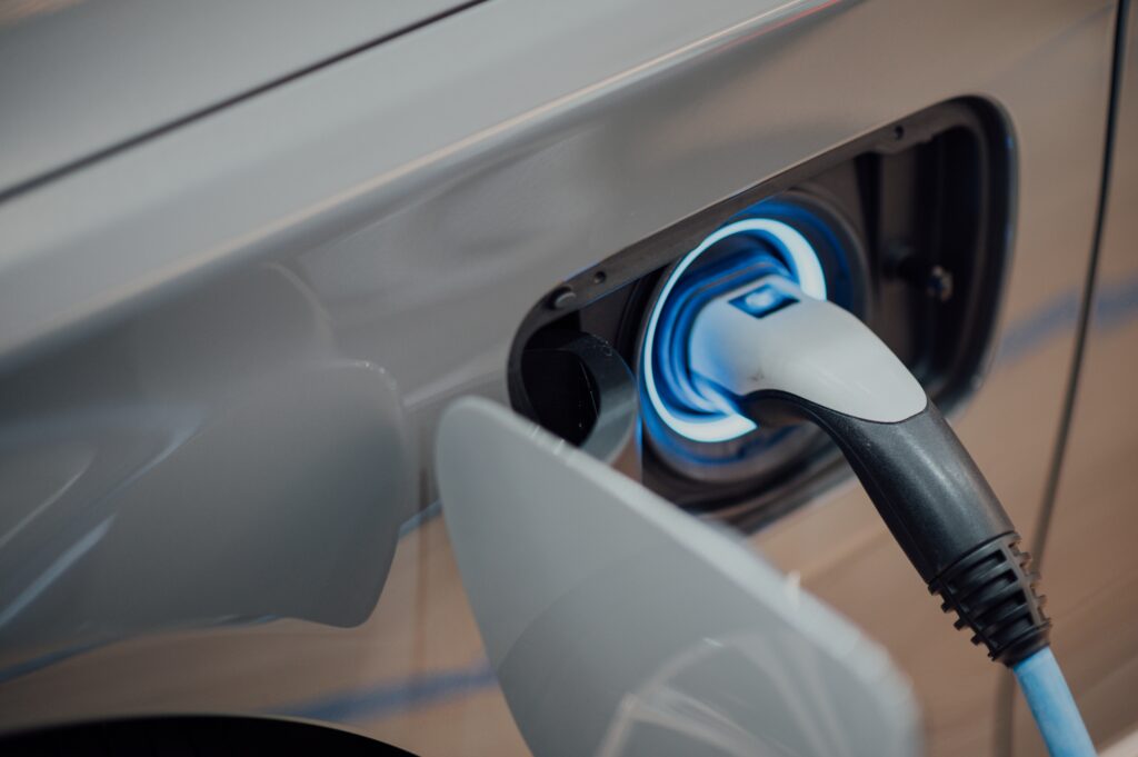 Electric car charging station power supply, featuring a close-up view of the plugged-in power supply charging an electric car.